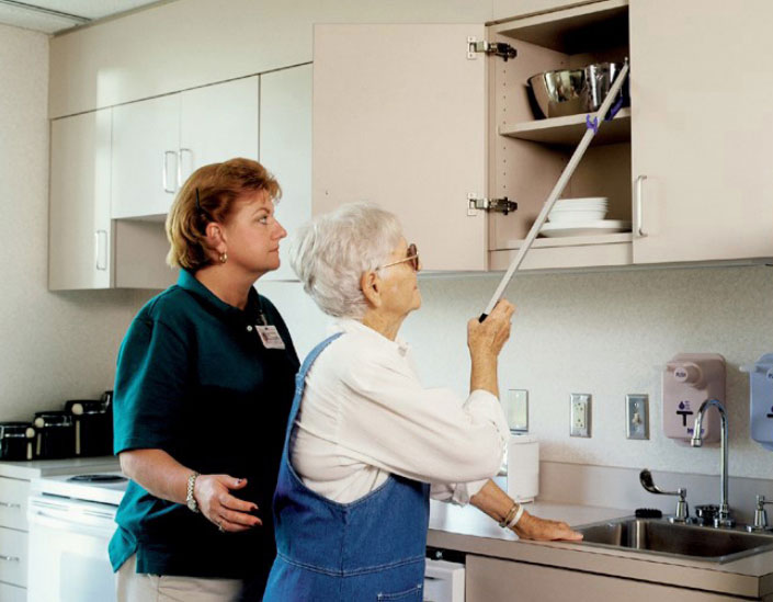 The worker helps a woman with visual impairment disability at the independent living center