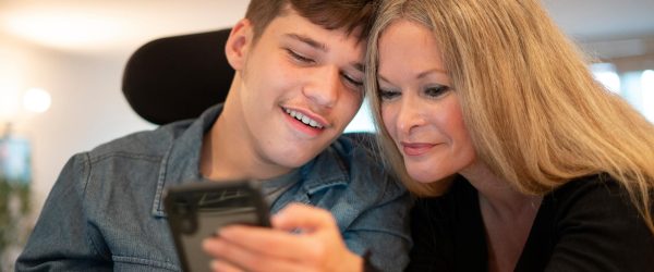 A young man and his mother look at his smartphone together.